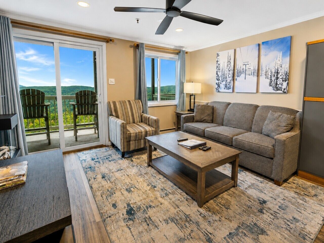 A living room with a sofa, armchair, coffee table, and a view of the outdoors through a sliding door.