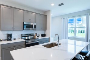 Enjoy cooking in this well-equipped kitchen with sleek cabinetry, stainless steel appliances, and a spacious island with a sink.