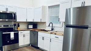 Uma cozinha moderna com armários brancos, eletrodomésticos de aço inoxidável e bancada de madeira.