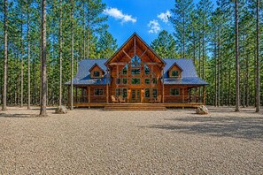 A log cabin with a symmetrical design, multiple windows, and a gravel driveway. - Awakening Dreams: Make Lasting Memories-Grand Lodge, Playset, Pool Table, Games (Broken Bow)