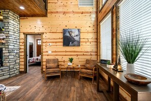 Cozy space with a stone fireplace, armchairs, and a large moose painting.