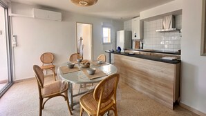 Una cocina moderna con una mesa redonda, sillas de mimbre y una lámpara colgante.