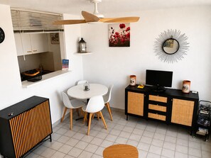 A compact living space with a dining area, a television, and a small kitchenette.