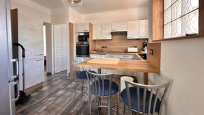Une cuisine moderne dotée d’un plan de travail en bois, d’appareils électroménagers en acier inoxydable et d’un coin repas avec des chaises en métal.