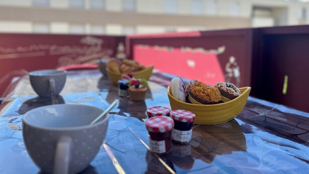 Une table avec un bol rempli de viennoiseries, une tasse et des pots de confiture.