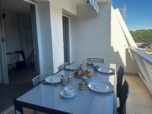 Un balcon avec une table dressée pour le petit-déjeuner, comprenant des croissants et des viennoiseries, et une vue sur les environs.