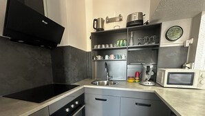 Une cuisine moderne dotée d’une plaque de cuisson à induction noire, d’appareils électroménagers en acier inoxydable et d’un four encastré.