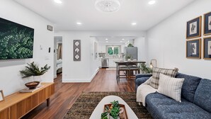 Un salon moderne avec un canapé bleu, un plancher en bois et un coin repas à l’arrière-plan.