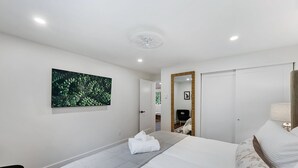 Une chambre d’hôtel avec un grand lit, un tableau au mur, un miroir et une porte donnant sur une autre pièce.