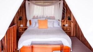 Ein Zimmer mit Holzboden, einem Bett, einem Nachttisch und einer Hängeleuchte.
