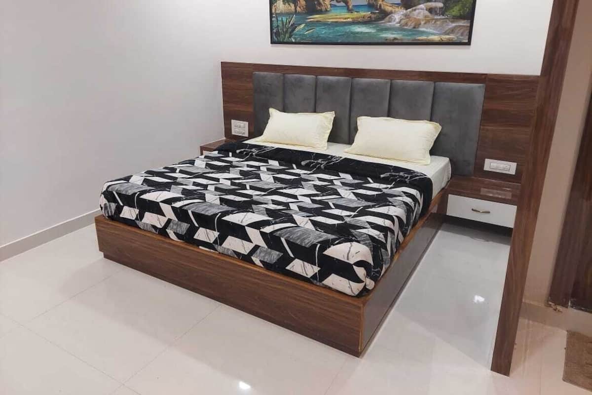 A bedroom with a bed, a headboard, a nightstand, and a painting on the wall.