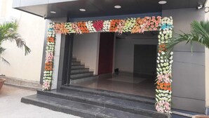 A building entrance with a floral archway and steps leading up to a dark interior. - Hotel Sri Balaji Inn  (Nirmal)