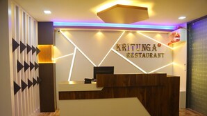 A reception desk with a modern design, featuring a wooden finish and a sign that reads "KRITUANGA RESTAURANT". - Hotel Sri Balaji Inn  (Nirmal)
