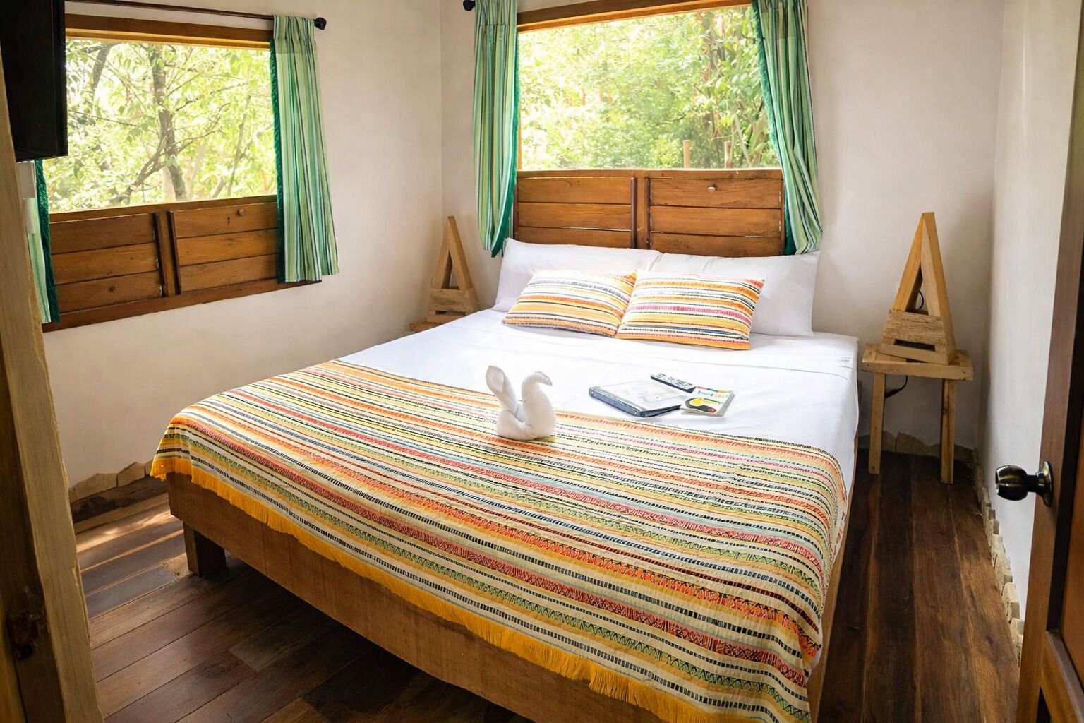 A bed with a striped blanket, pillows, a white swan decoration, and a wooden headboard.