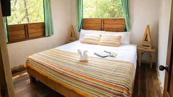 A bed with a striped blanket, pillows, a white swan decoration, and a wooden headboard.