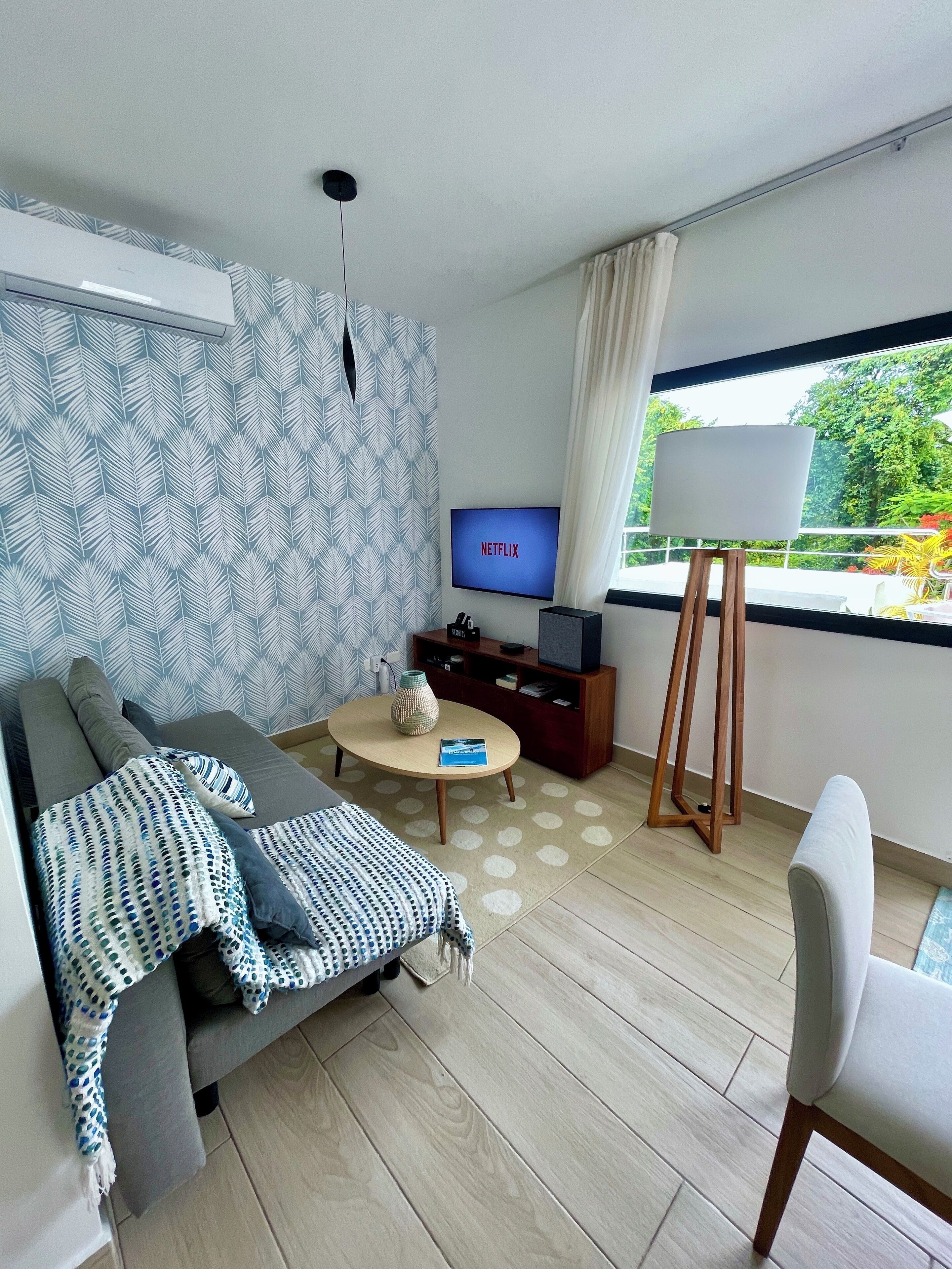 A modern living room with a sofa, coffee table, and a TV displaying 'NETFLIX'.
