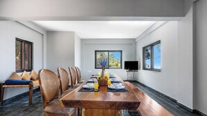 A dining area with a long wooden table set for six, surrounded by wicker chairs. - Lazy Hills by Xplore Indo (Kotagiri)