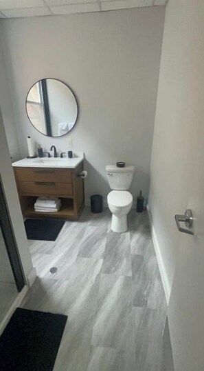 Een kleine, moderne badkamer met toilet, wastafel en spiegel.