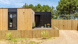 A modern wooden house with a black door and window, surrounded by a wooden fence and potted plants. - Modern House near the Beach (Punta Ballena)