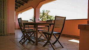 Un comedor con mesa y sillas, una botella de vino y vistas al exterior con vegetación.
