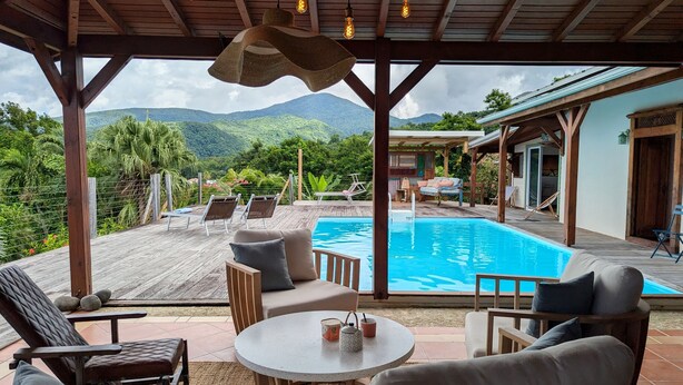 Un espace extérieur abrité comprenant une piscine, des chaises longues et une table.