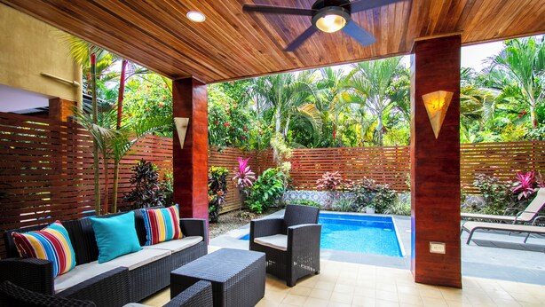 A covered outdoor area with wicker furniture, a pool, and lush tropical plants. - 3 min walk to surf, 3bedrooms, Villa, Pool, Steps to the Beach! (Uvita)