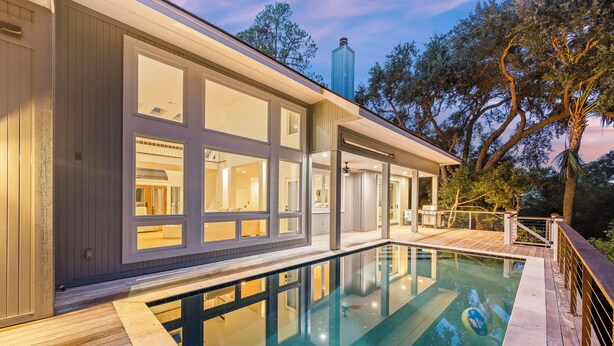 A modern house with a swimming pool, large windows, and a deck area. - Beautiful Bluebill Home on Kiawah, Private Pool, Pond and Golf Views! (Kiawah Island)