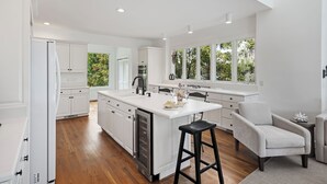 A modern kitchen with white cabinetry, a central island, and a bar stool. - Beautiful Bluebill Home on Kiawah, Private Pool, Pond and Golf Views! (Kiawah Island)