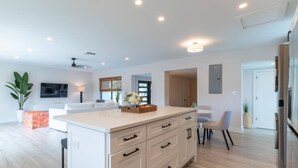 A modern kitchen with a central island, white cabinetry, and a dining area with a table and chairs.
