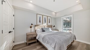 A bedroom with a bed, nightstands, a window, and a door.
