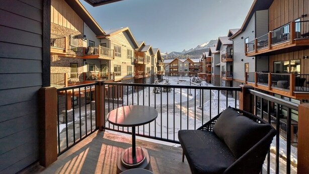 A balcony with a view of a snow-covered courtyard and mountain backdrop.