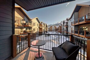 Un balcón con vistas a un patio nevado y a montañas al fondo.