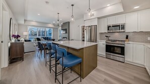 A modern kitchen with white cabinets, stainless steel appliances, and a central island with bar stools.