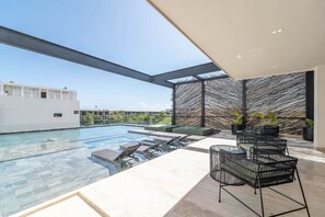 A rooftop infinity pool with lounge chairs and a modern design. - Lux 1BR w/ Rooftop Pool, Close to Beach (Tulum)