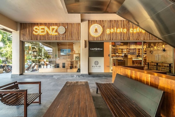 A modern outdoor seating area with wooden benches and a café named 'gelato cafe' in the background.