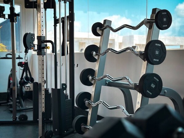 Une salle de sport équipée de matériel de musculation, notamment un support à squats et des haltères réglables.