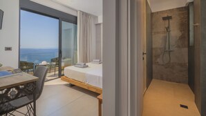 Une chambre moderne dotée d’une grande porte-fenêtre coulissante donnant sur un balcon avec vue sur la mer.