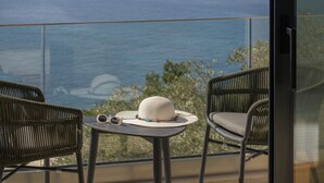Un balcon avec des fauteuils en osier, une petite table et une vue sur la mer.