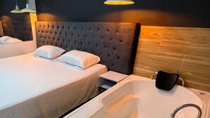 Une chambre d’hôtel avec deux lits, une grande baignoire et des luminaires suspendus.