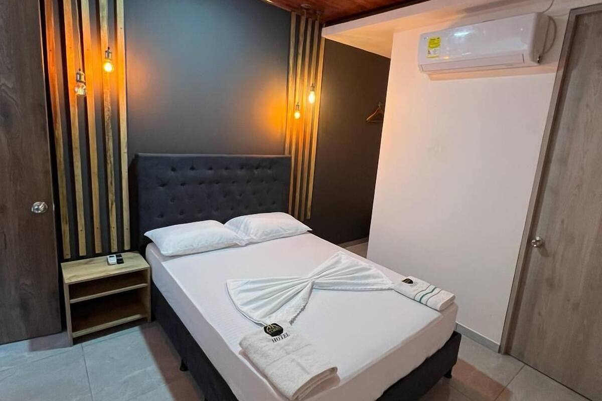 A hotel room with a bed, a nightstand, a wardrobe, and a ceiling light.