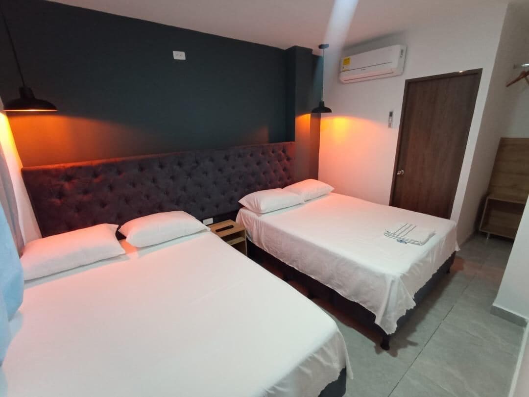 Ein Hotelzimmer mit zwei Einzelbetten, einem dunklen Kopfteil und einem Holzschrank.
