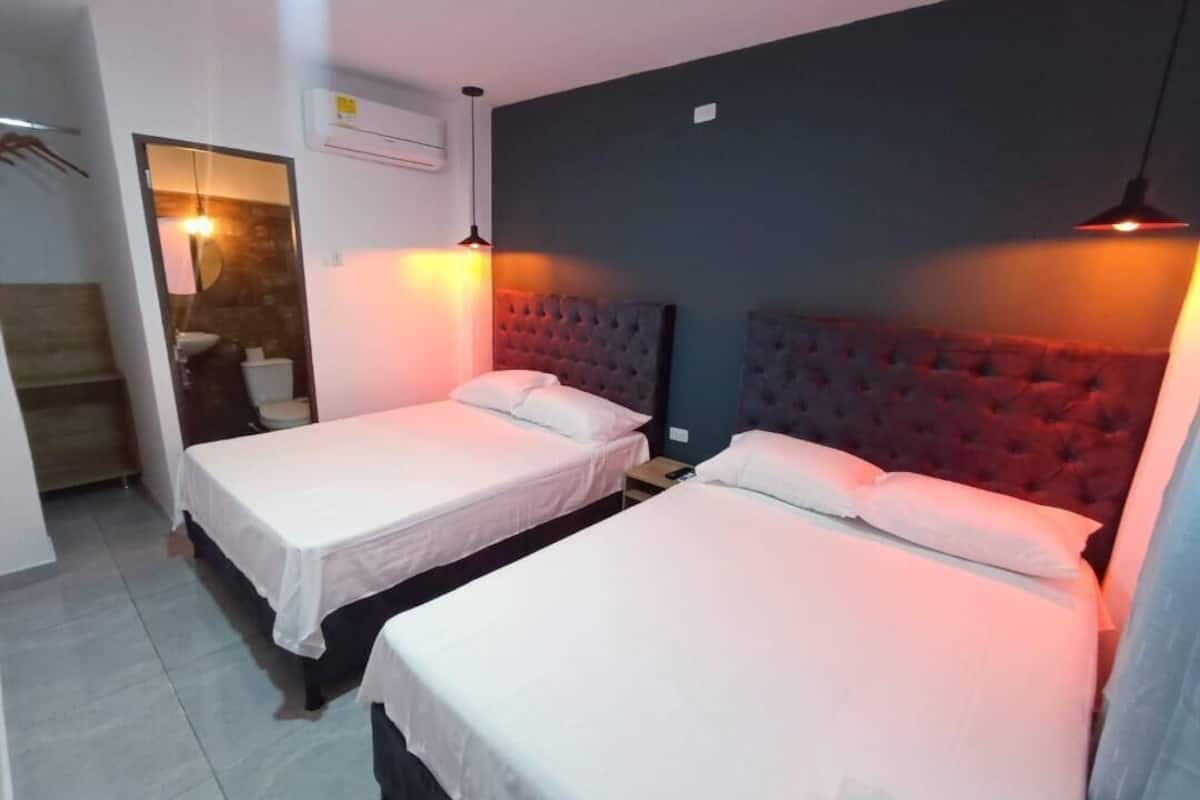 A room with two beds, a mirror, an air conditioning unit, and a hanging light fixture.