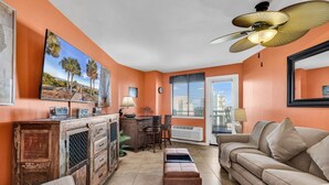 A living room with a sofa, a coffee table, a fireplace, a dining table with chairs, and a ceiling fan. - Bluewater Resort 1012 (Myrtle Beach)