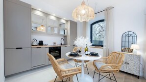 A modern kitchen with grey cabinets, a round dining table, wicker chairs, and a hanging light fixture. - Łódź Downtown - Parking & Balcony - by Rentujemy (Łódź)