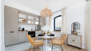 A modern kitchen with grey cabinets, a round dining table with wicker chairs, and a decorative cabinet with a geometric pattern. - Łódź Downtown - Parking & Balcony - by Rentujemy (Łódź)