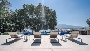 Un espace aménagé au bord de la piscine, avec des chaises longues et une vue sur la mer.
