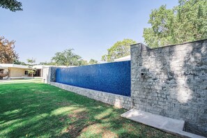 A modern outdoor area with a stone wall and a blue mosaic wall.