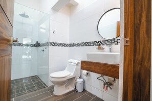 A modern bathroom with a glass-enclosed shower, a white toilet, and a wooden vanity with a sink.