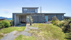 Une maison moderne à deux étages, dotée d’un porche abrité et d’un petit jardin.