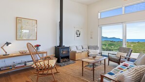 Un salon chaleureux avec une grande fenêtre, une cheminée et des sièges confortables.